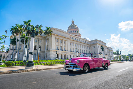 A vintage American retro carconvertible rides on an asphalt road in front of the Capitol in old town Havana. Tourist taxi cabriolet.のeditorial素材