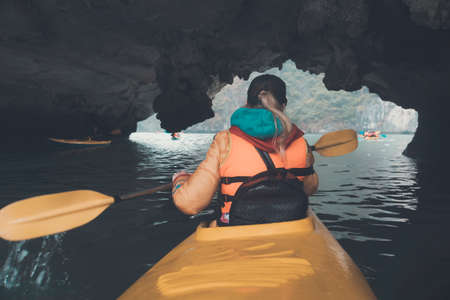 Woman explores caves with kayak. Woman floating on a yellow kayak inside the cave. Vietnam ha long...