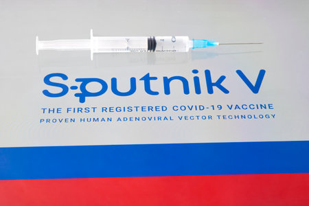 The vaccine Sputnik V from the coronovirus infection covid-19 and a syringe on background russian flag. January 18, 2021, Barnaul, Russia.のeditorial素材