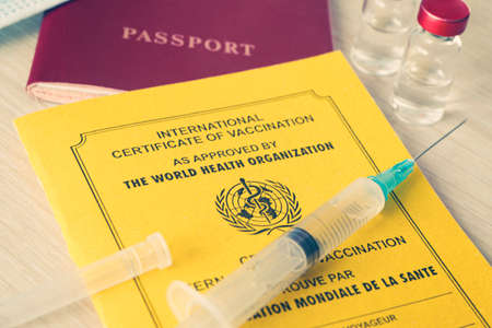 International Certificate of Vaccination with a Syringe, passport of a foreign citizen and a Ampule on the table.の写真素材