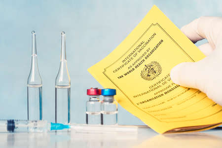 the International Certificate of vaccination, the syringe and ampoules are on the table in the lab....