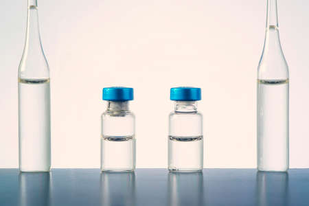 clear glass tubes of liquid stands on a table against a blue background. The concept of laboratory research. The vaccine is in a bottle. A test tube for inoculation. copy space,の写真素材