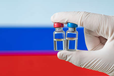 Russia flag with  virus  concept. Doctor with protection medical gloves holding a vaccine bottle.  virus outbreaking. concept of mass vaccination against  virusの写真素材