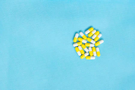 White and yellow pills set flat lay for medicine content with copy space on blue background. Top view of vitamin supplements. Medical concept.の写真素材