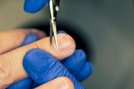 The man on procedures in manicure salon. Spa, manicuring, removal of cuticles scissors. Beautiful male hands.の写真素材