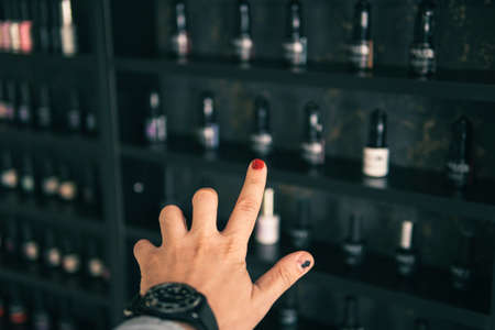 male hand selecting nail polish from multicolored palette in beauty salon. Shopping in beauty shopの写真素材