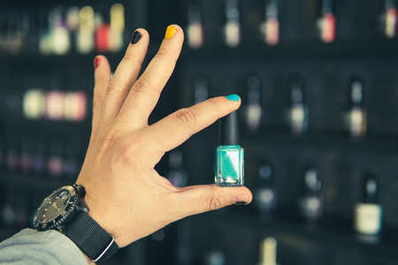 Bottle of nail polish in a man's hand with painted nails A man with painted nails. Design of male nails. men manicure.の写真素材