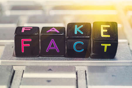 Black cubes change wording from fake to fact on a gray laptop keyboard. concept of fact-tampering. False news on the Internet. fake newsの写真素材