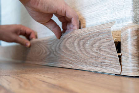 Man hands intall floor plastic skirting boards. replacement of the plastic skirting board on the floor.の写真素材