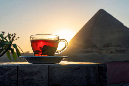 Having mint tea at an cafe while contemplating the impressive three pyramids of Giza. Transparent glass mug with black tea and mint on the background of the Egyptian pyramids.の写真素材
