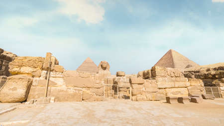Great Sphinx with pyramid in the background on a beautiful blue sky day in Giza, Cairo, Egypt.