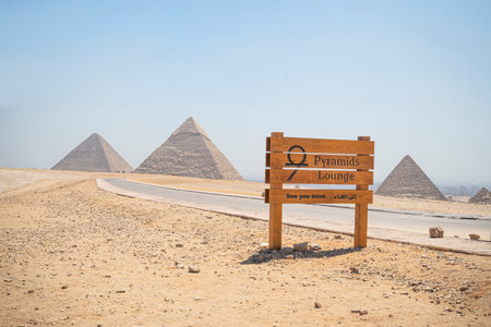 Archaeological complex of the Great Egyptian Pyramids is located on the Giza plateau, in the Libyan desert, on the left bank of the Nile. a sign on the road in front of the pyramids.のeditorial素材