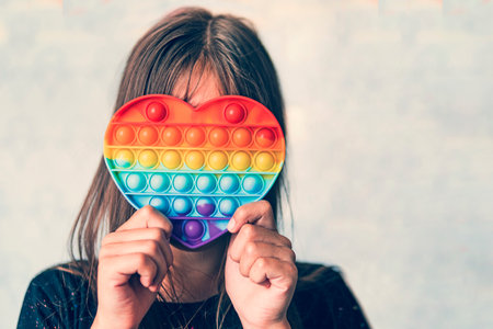 Cute faceless child playing with the  fidget. Push pop bubble flexible fidget sensory toy provide discharge and are good for the development of kid.の写真素材