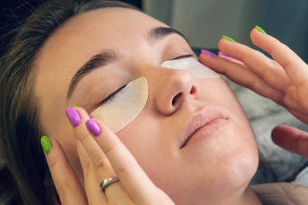 Woman With Eye Patches, Relaxing In Spa Center. girl herself makes a cosmetic procedure