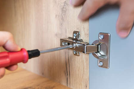 Concept of home repairing. A hand of a furniture assembler adjusting a mechanism for opening the...