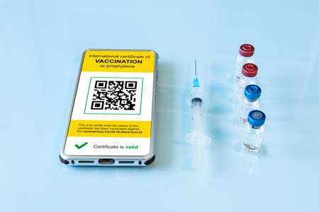 Digital immunity passport with a  vaccination stamp and qr-code on a smartphone screen with vaccine,...