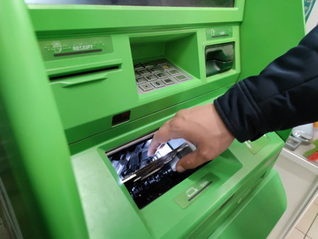 Hand of a man with a credit card, using an ATM. Man using an atm machine with his credit card.