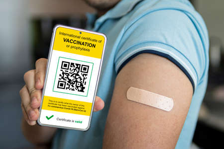 Man shows health passport of vaccination certification on phone and a shoulder with a taped-up...