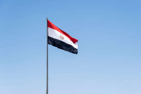 National flag of Egypt on flagpole in front of blue skyの写真素材