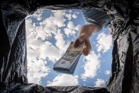 throwing away dollars in trashcan. Getting rid of excess cash, switching to non-cash payment. The...