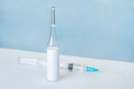 close-up of small ampoule with empty label and syringe defocused blurred on background. macro shot with copy space. vaccine epidemic medical research conceptの写真素材