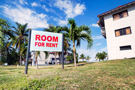 Sign board with text ROOM FOR RENT near modern building in the rural countryside. Rent houses and rooms in a beautiful resort area near the coastの写真素材