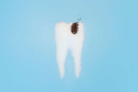 Sugar destroys tooth enamel and leads to tooth decay. Sugar are laid out in the form of a tooth and coffee symbolizes caries.の写真素材