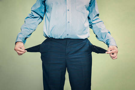 concept no money. businessman standing on the green background and showing his empty pocket, turning his pocket inside out,の写真素材