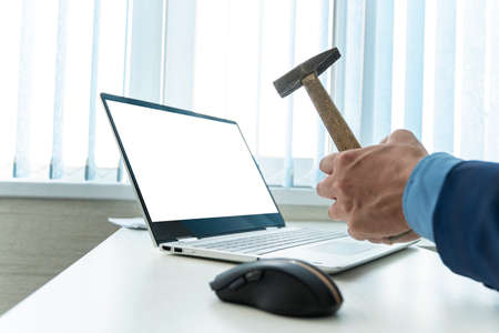 Person hitting a laptop screen with a hammer in frustration. empty blank laptop screen for design, text message. copy spaceの写真素材