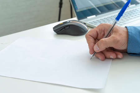 Male hand with pen writing on a blank sheet of paper. copy space for text and design. a hand with a...