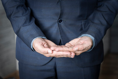 Close-up side view of the hands of an unidentified young man in shirt and jacket holding an invisible object on palm. The concept of caring hands. Advertising conceptの写真素材