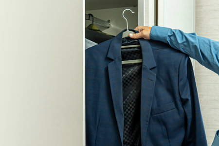 Businessman dressing up for work. A young male businessman chooses a jacket. Dress code at work.の写真素材