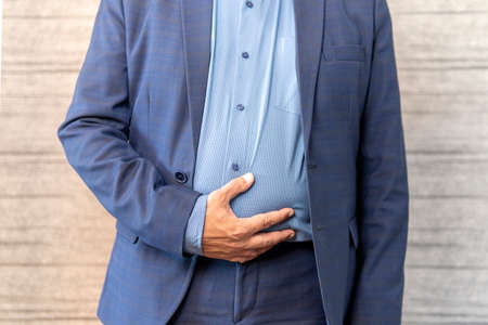 Indigestion of the intestines from poor-quality food. Diarrhea concept. Businessman having stomachache because of eating junk food.の写真素材