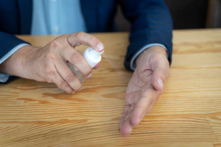Applying alcohol sanitizer spray or antibacterial spray at arm to prevent spread of virus, bacteria...