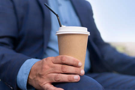 Handsome businessman enjoying on pause and drinking coffee to go. paper cup of coffee in a man's...