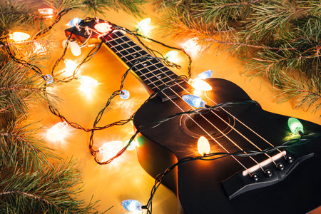 black ukulele guitar and christmas decorations on the dark background. hawaiian guitar with lighted...