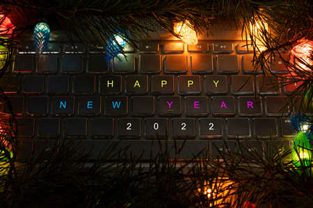 HAPPY NEW YEAR 2022 written on keyboard and lights of garlands in the dark at nightの写真素材