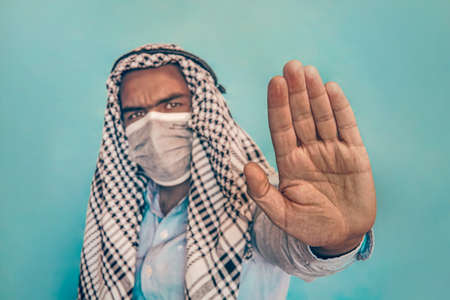 Arab man with face medical mask showing stop gesture. People, healthcare and medicine concept. entrance without a mask is prohibitedの写真素材