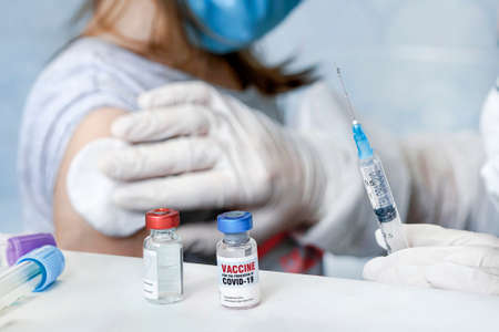 doctor is injecting medicine for treatment or a vaccine to prevent corona virus or Covid 19 in the arms of an girl. Large-scale vaccination to protect population from coronavirus sars-cov-2の写真素材