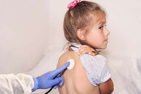 Close-up doctor hand with stethoscope. Health check in pediatric office. Pediatrician examining little child with stethoscope. Medical examination of little girl. Professional clinical diagnostics.の写真素材