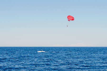 Sport activity - Parasailing over the Mediterranean sea. A speedboat pulls a yellow parachute with a tourist. Extreme entertainment for tourists on the sea.の写真素材