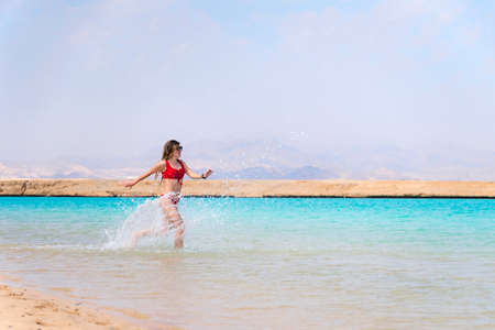Pretty woman having fun on beach red swimsuit leisure nature caribbean islandsの写真素材