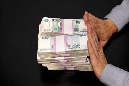 million rubles in men's hands. Bribery in Russian rubles in a dark room. The concept of corruption...