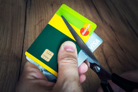 April 2, 2022 Russia: a man cuts bank credit cards of the type and mastercard with scissors. Destruction of plastic cards after the expiration date.のeditorial素材