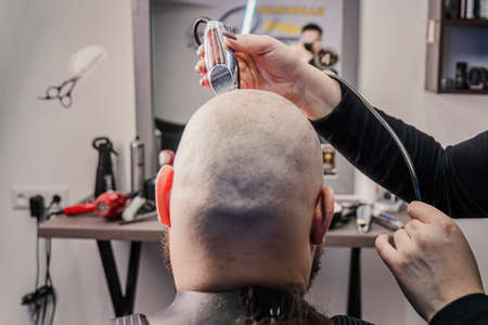 Middle aged caucasian man is cutting his own hair with electric razor.の写真素材