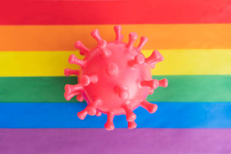 The rubber virus lies on the rainbow flag. The concept of the risk of contracting a virusの写真素材