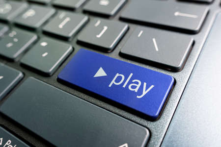 A colored button with the inscription play on a black keyboard.の写真素材