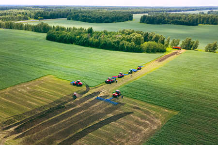 Tractor with plow on soil cultivating. tractor bowling field, drone view. Cultivated plant and soil tillage. Agricultural tractors on field cultivation. Tractor disk harrow on plowing farm field.の写真素材