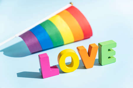 Love word with LGBT rainbow flag on blue background. Happy Pride month. Declaration of different kinds of love. LGBT rights. selective focusの写真素材