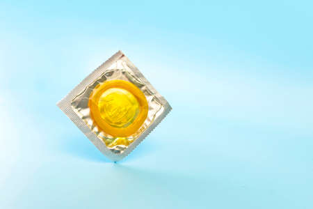 A yellow condom on a blue background .copy space for text and designの写真素材
